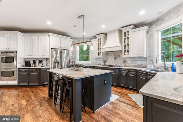 13128 Kahns Rd, Manassas, VA 20112 - kitchen featuring custom exhaust hood, stainless steel appliances, a sink, white cabinetry, and backsplash