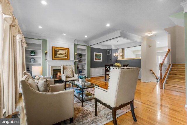 6249 Auburn Leaf Ln, Alexandria, VA 22312 - living room with light wood-type flooring, a glass covered fireplace, crown molding, a chandelier, and built in features