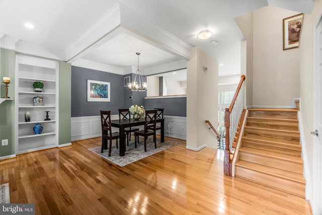 6249 Auburn Leaf Ln, Alexandria, VA 22312 - dining space with a chandelier, wood-type flooring, ornamental molding, built in shelves, and a wainscoted wall
