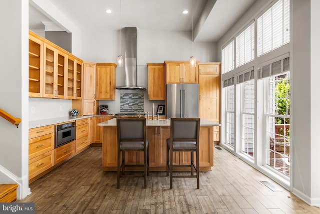 6249 Auburn Leaf Ln, Alexandria, VA 22312 - kitchen with high end refrigerator, wall chimney exhaust hood, dark wood-style floors, a towering ceiling, and a center island with sink