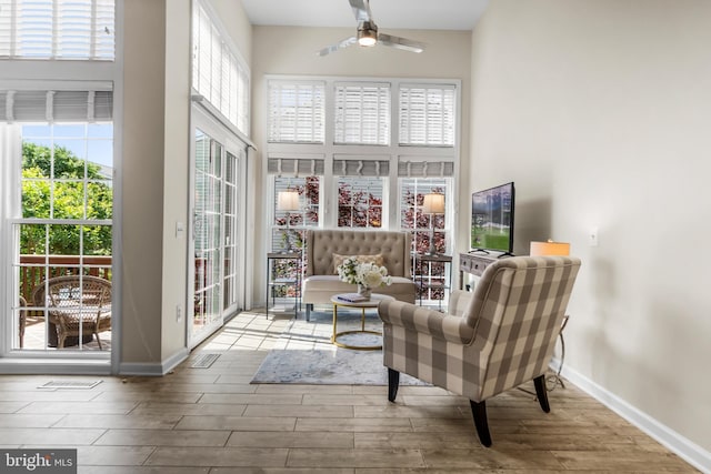 6249 Auburn Leaf Ln, Alexandria, VA 22312 - sitting room featuring wood finished floors, a ceiling fan, a high ceiling, and plenty of natural light