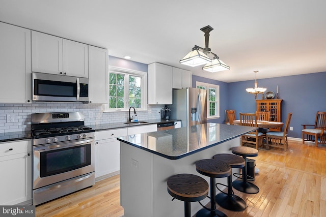 207 Wilshire Ln, Newark, DE 19711 - kitchen with stainless steel appliances, a sink, light wood-style flooring, tasteful backsplash, and a center island
