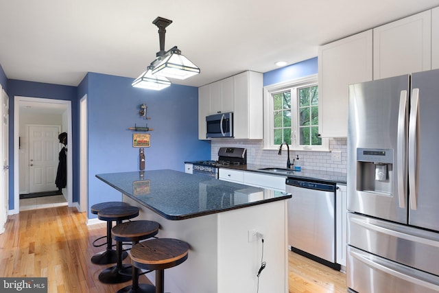 207 Wilshire Ln, Newark, DE 19711 - kitchen with appliances with stainless steel finishes, a sink, white cabinets, a breakfast bar, and tasteful backsplash