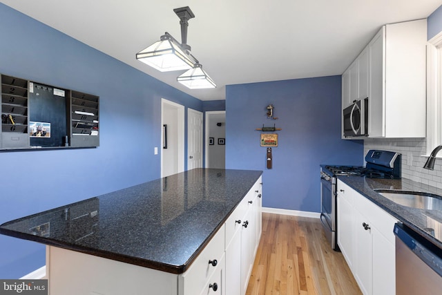 207 Wilshire Ln, Newark, DE 19711 - kitchen with stainless steel appliances, a sink, white cabinets, light wood finished floors, and tasteful backsplash