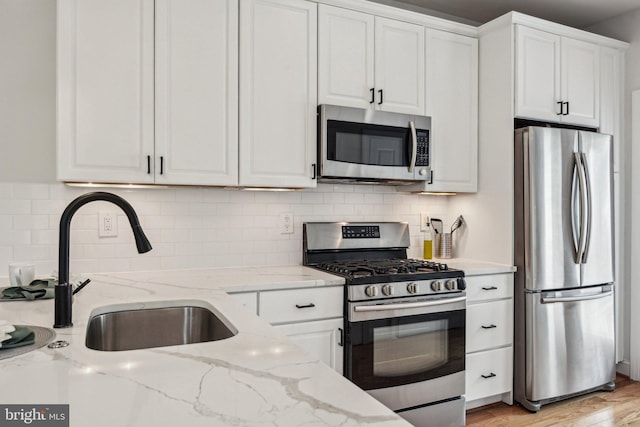 300 15th St SE, Washington, DC 20003 - kitchen with appliances with stainless steel finishes, white cabinets, a sink, decorative backsplash, and light stone countertops