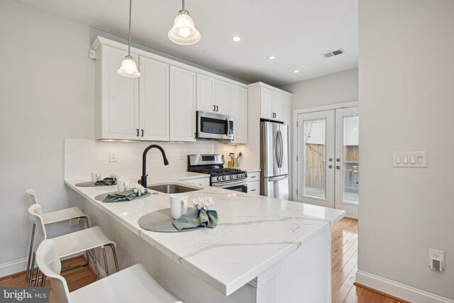 300 15th St SE, Washington, DC 20003 - kitchen featuring stainless steel appliances, a sink, light wood finished floors, backsplash, and baseboards