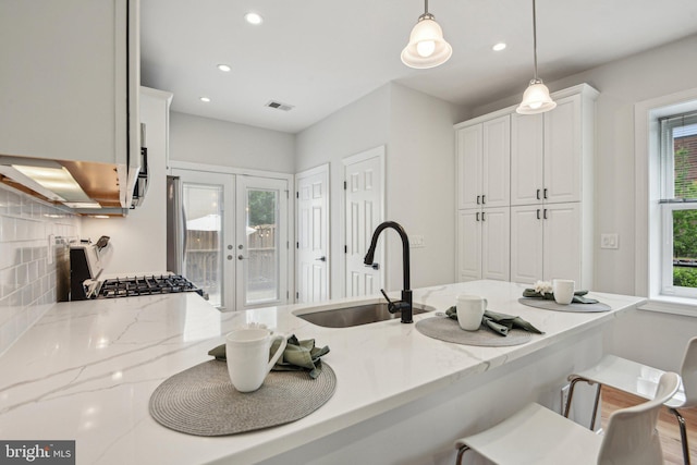 300 15th St SE, Washington, DC 20003 - kitchen featuring a sink, french doors, a kitchen breakfast bar, white cabinets, and light stone countertops