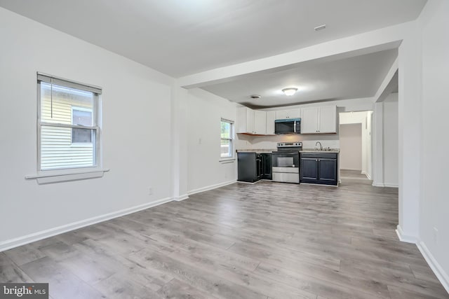 227 Elizabeth Ave, Baltimore, MD 21225 - kitchen featuring electric range, stainless steel microwave, light countertops, white cabinetry, and light wood finished floors