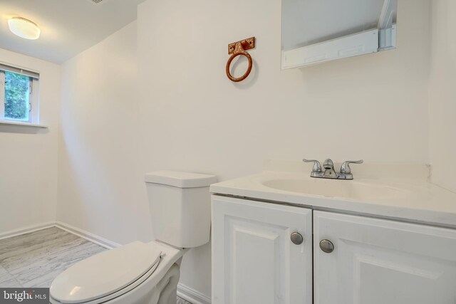 227 Elizabeth Ave, Baltimore, MD 21225 - half bath with toilet, vanity, wood finished floors, and baseboards