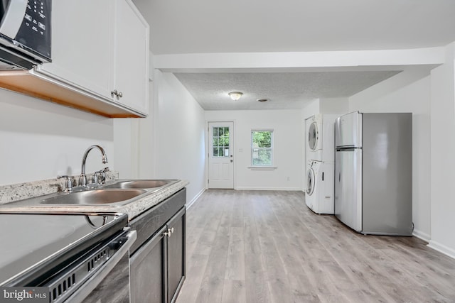 227 Elizabeth Ave, Baltimore, MD 21225 - kitchen featuring black appliances, estacked washer and dryer, a sink, light wood finished floors, and a textured ceiling