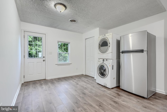 227 Elizabeth Ave, Baltimore, MD 21225 - laundry area featuring stacked washer / drying machine, a textured ceiling, light wood finished floors, and baseboards