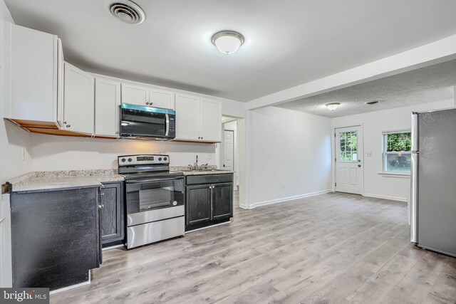 227 Elizabeth Ave, Baltimore, MD 21225 - kitchen featuring stainless steel appliances, light wood finished floors, white cabinetry, baseboards, and a sink