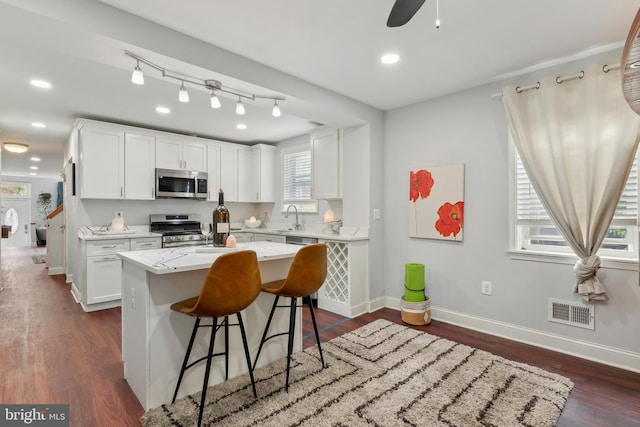 202 E Lafayette Ave, Baltimore, MD 21202 - kitchen with appliances with stainless steel finishes, white cabinets, baseboards, a breakfast bar area, and a center island