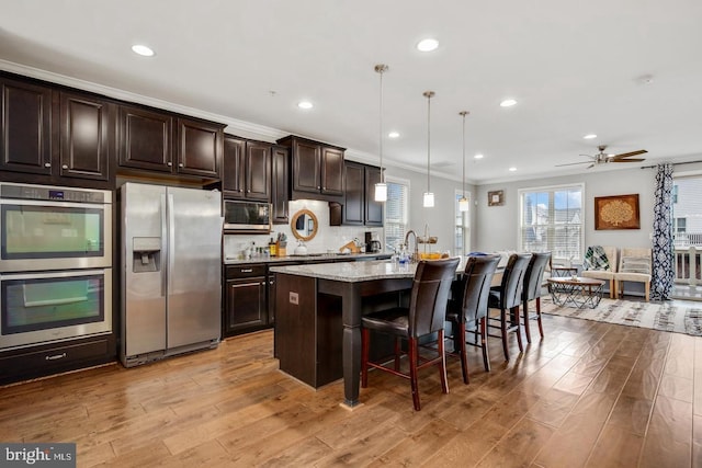 13304 Windy Meadow Ln, Silver Spring, MD 20906 - kitchen featuring stainless steel appliances, ornamental molding, a kitchen bar, a center island with sink, and wood finished floors