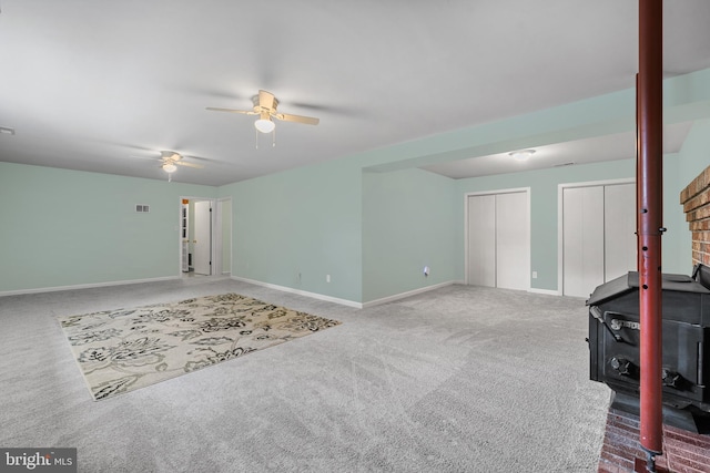 23359 Patuxent View Rd, Lexington Park, MD 20653 - unfurnished living room featuring a wood stove, carpet, a ceiling fan, and baseboards