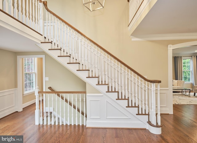 529 Sugartown Rd, Berwyn, PA 19312 - stairway featuring wood finished floors, a wainscoted wall, a decorative wall, a high ceiling, and ornamental molding