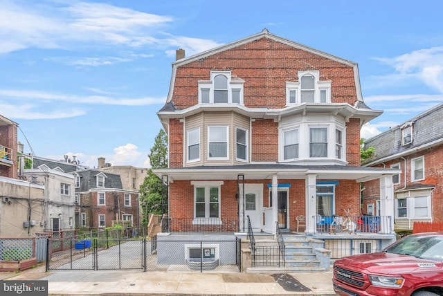 10 W Pomona St, Philadelphia, PA 19144 - townhome / multi-family property with covered porch, a gate, brick siding, and a fenced front yard