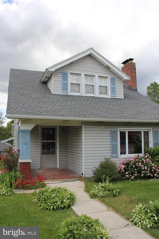 5077 Lincoln Hwy W, Thomasville, PA 17364 - view of front of house featuring a porch, a chimney, roof with shingles, and a front yard