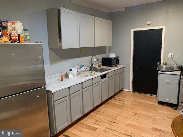 1632 Park St, Harrisburg, PA 17103 - kitchen featuring freestanding refrigerator, gray cabinetry, a sink, light wood-type flooring, and crown molding