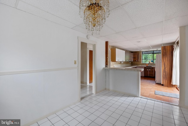3962 Bensalem Blvd, Bensalem, PA 19020 - kitchen with stainless steel counters, a paneled ceiling, light tile patterned floors, freestanding refrigerator, and a peninsula
