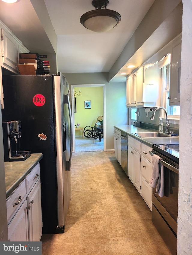 302 Old Lancaster Rd, Devon, PA 19333 - kitchen with stainless steel appliances, a sink, white cabinets, light flooring, and baseboards
