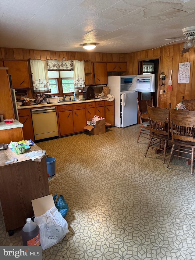 81 Hollering Hill Rd, Camden Wyoming, DE 19934 - kitchen featuring dishwasher, light countertops, wood walls, freestanding refrigerator, and brown cabinets
