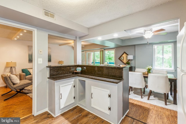 11833 Shire Ct Unit 12C, Reston, VA 20191 - kitchen with wood finished floors, dark stone counters, white cabinetry, a ceiling fan, and a textured ceiling
