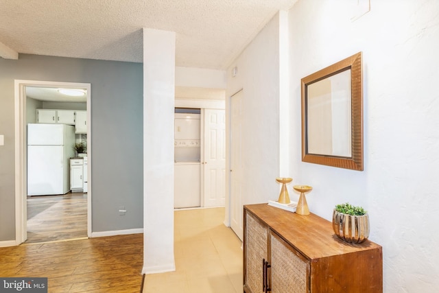 11833 Shire Ct Unit 12C, Reston, VA 20191 - hallway with estacked washer and dryer, a textured ceiling, baseboards, and light wood finished floors