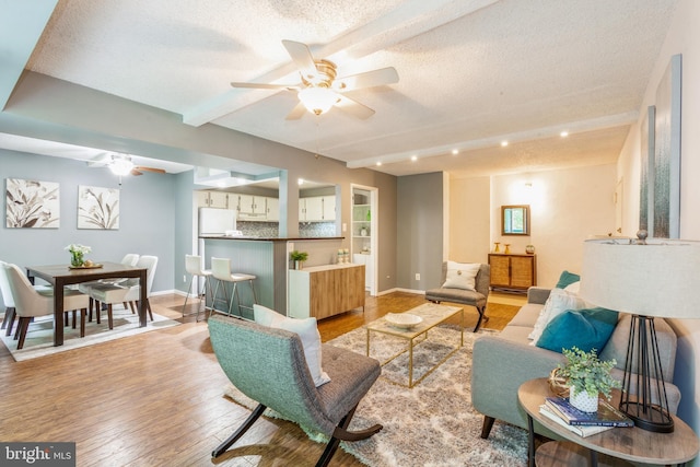 11833 Shire Ct Unit 12C, Reston, VA 20191 - living room featuring a ceiling fan, light wood-style flooring, beamed ceiling, a textured ceiling, and baseboards