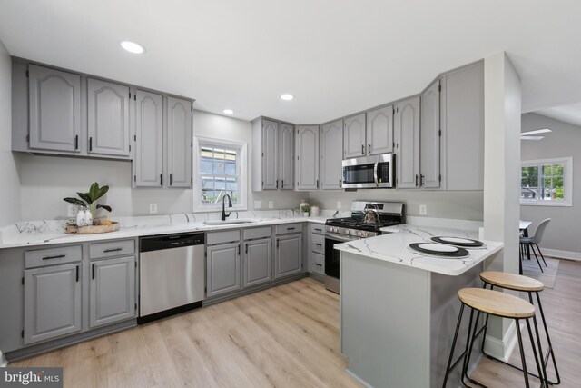 3521 Forestdale Ave, Woodbridge, VA 22193 - kitchen with gray cabinets, appliances with stainless steel finishes, a sink, light wood finished floors, and a peninsula