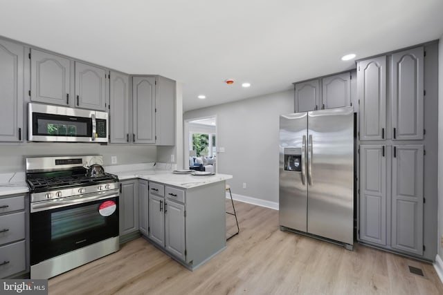 3521 Forestdale Ave, Woodbridge, VA 22193 - kitchen featuring appliances with stainless steel finishes, gray cabinets, a peninsula, light wood-style flooring, and recessed lighting