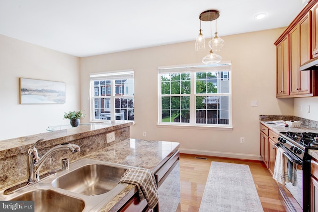 2505 Basin View Ln, Woodbridge, VA 22191 - kitchen featuring a sink, stainless steel gas stove, light wood-style flooring, baseboards, and pendant lighting