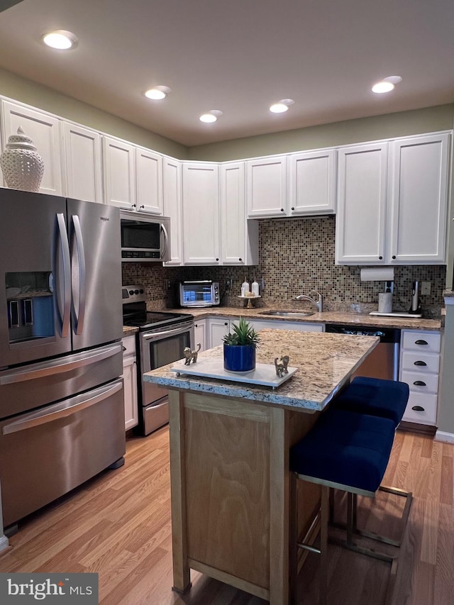 7884 Seafarer Way, Lorton, VA 22079 - kitchen featuring appliances with stainless steel finishes, a sink, light wood finished floors, a center island, and decorative backsplash