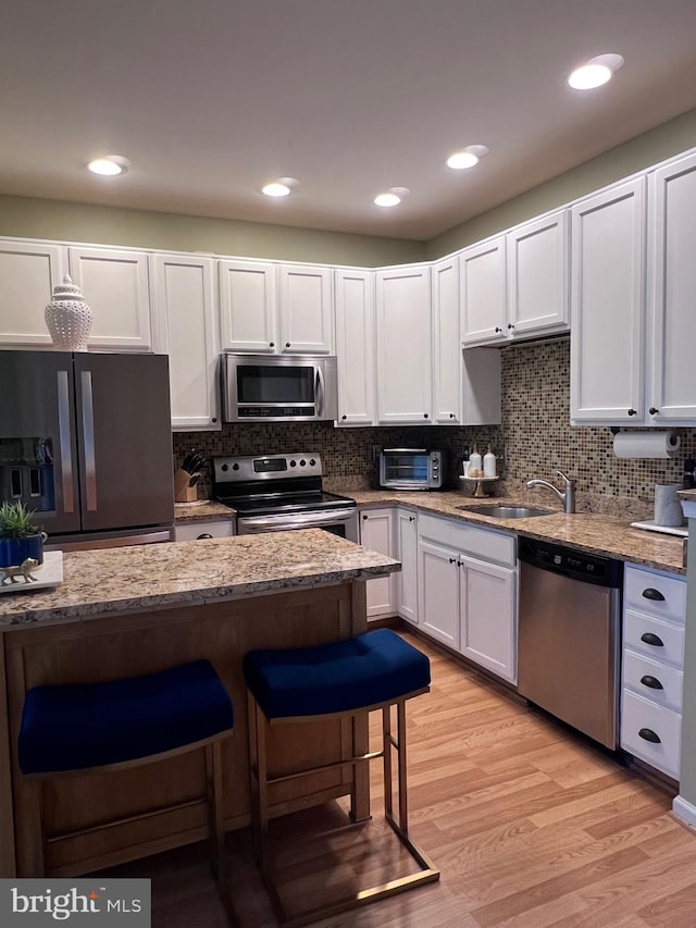 7884 Seafarer Way, Lorton, VA 22079 - kitchen featuring appliances with stainless steel finishes, a sink, light wood-style floors, and light stone countertops