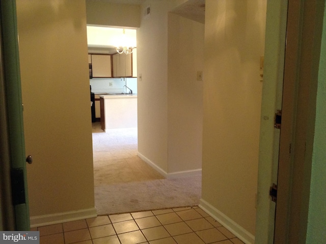 406 Deer Run, Norristown, PA 19403 - hallway featuring light carpet, a chandelier, baseboards, light tile patterned floors, and a sink