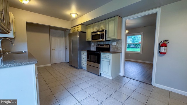 40 Marshal Ln, Willingboro, NJ 08046 - kitchen with stainless steel appliances, a sink, light tile patterned floors, backsplash, and cream cabinetry