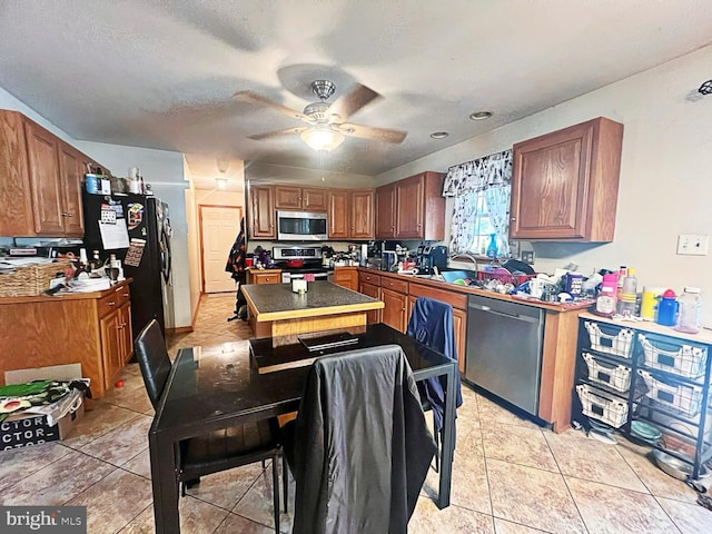 169 Fieldbrook Dr, Magnolia, DE 19962 - kitchen featuring appliances with stainless steel finishes, a center island, ceiling fan, light tile patterned floors, and brown cabinetry