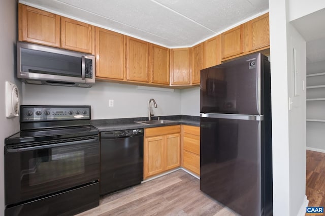 30 Spring Ct, Charlottesville, VA 22901 - kitchen with black appliances, a sink, light wood-type flooring, and dark countertops