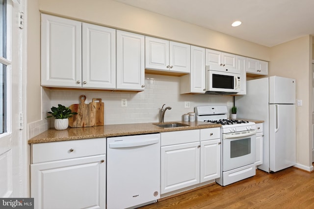 417 Gibbon St, Alexandria, VA 22314 - kitchen with white appliances, a sink, white cabinets, light wood-style flooring, and backsplash