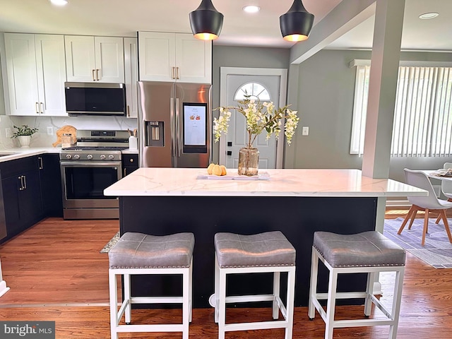 3408 Croydon Rd, Gwynn Oak, MD 21207 - kitchen with appliances with stainless steel finishes, a breakfast bar area, light stone counters, white cabinets, and recessed lighting