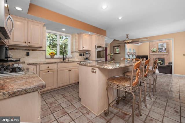 1224 Highland Dr, Orefield, PA 18069 - kitchen with appliances with stainless steel finishes, a sink, decorative backsplash, a breakfast bar area, and a ceiling fan