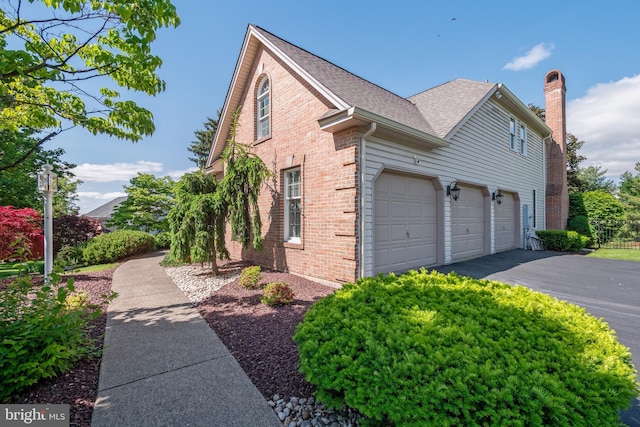 1224 Highland Dr, Orefield, PA 18069 - view of home's exterior featuring brick siding, a chimney, driveway, a garage, and roof with shingles