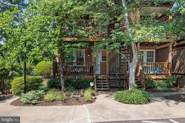 3 Russell Rd Unit 3B, Alexandria, VA 22301 - view of front facade with stairway, brick siding, a wooden deck, and covered porch