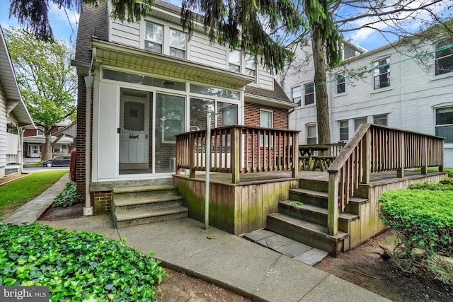 827 Pennsylvania Ave, York, PA 17404 - view of front of house with a deck, brick siding, a shingled roof, and a sunroom