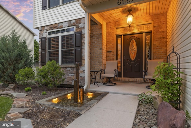 6133 Jennifer Ln, Spring Grove, PA 17362 - exterior entry at dusk featuring stone siding, a porch, and brick siding
