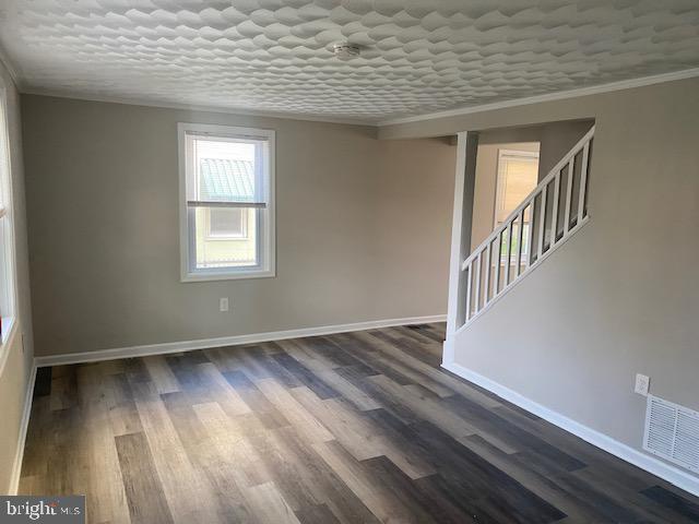 1311 Sycamore Ave, Wilmington, DE 19805 - unfurnished room with crown molding, dark wood-style floors, baseboards, and stairs