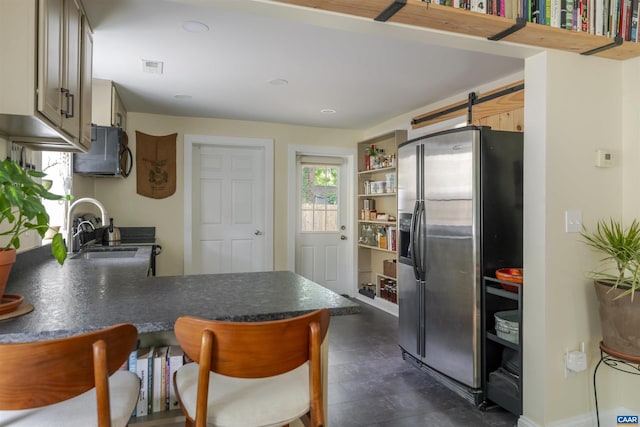 304 NW 11th St, Charlottesville, VA 22903 - kitchen with stainless steel fridge, a peninsula, dark countertops, a sink, and a kitchen breakfast bar