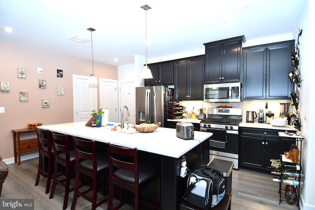 10401 Resort Rd Unit F, Ellicott City, MD 21042 - kitchen featuring stainless steel appliances, dark cabinetry, light countertops, a kitchen breakfast bar, and light wood-type flooring