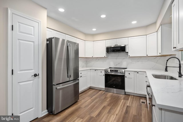 22 Buck Rd, Stafford, VA 22556 - kitchen with appliances with stainless steel finishes, a sink, dark wood-style floors, decorative backsplash, and white cabinetry