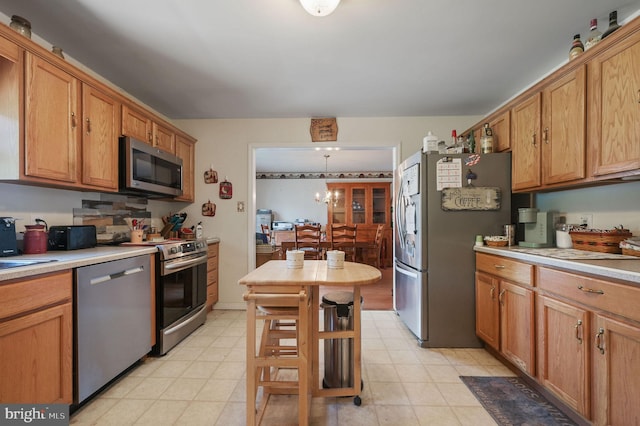 24519 Cedar Ln, Georgetown, DE 19947 - kitchen with appliances with stainless steel finishes, light countertops, brown cabinetry, light floors, and a chandelier